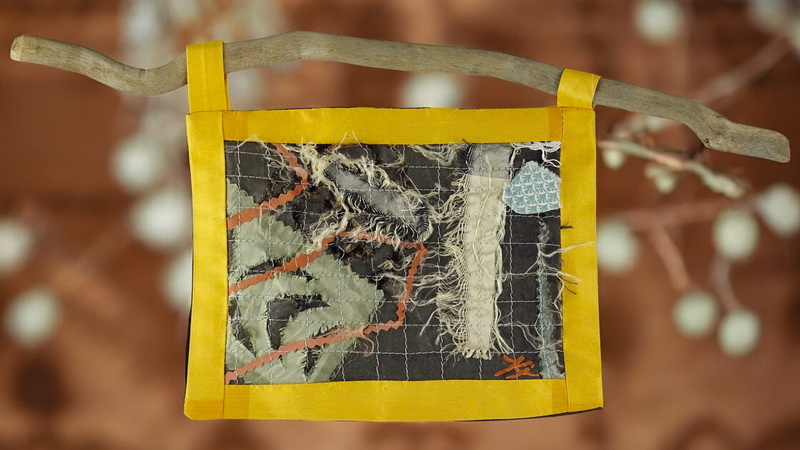 Œuvre textile suspendue en patchwork artistique sur support en bois flotté, mélange de soie, coton et fils apparents, inspirée du boro japonais et du wabi-sabi