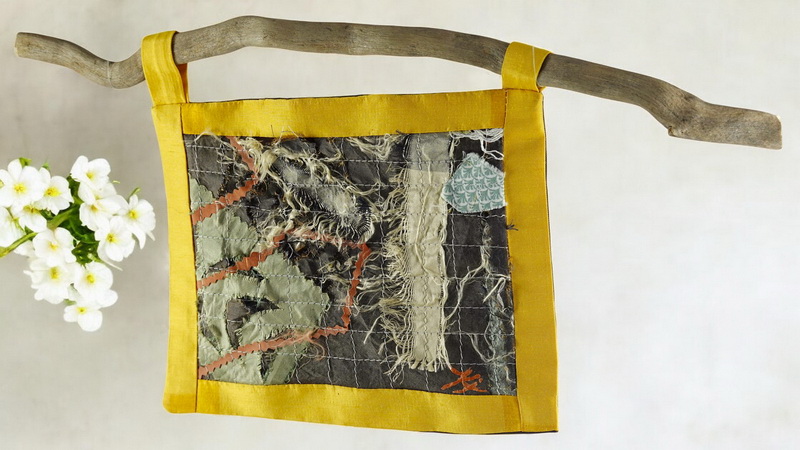 Œuvre textile suspendue en patchwork artistique sur support en bois flotté, mélange de soie, coton et fils apparents, inspirée du boro japonais et du wabi-sabi